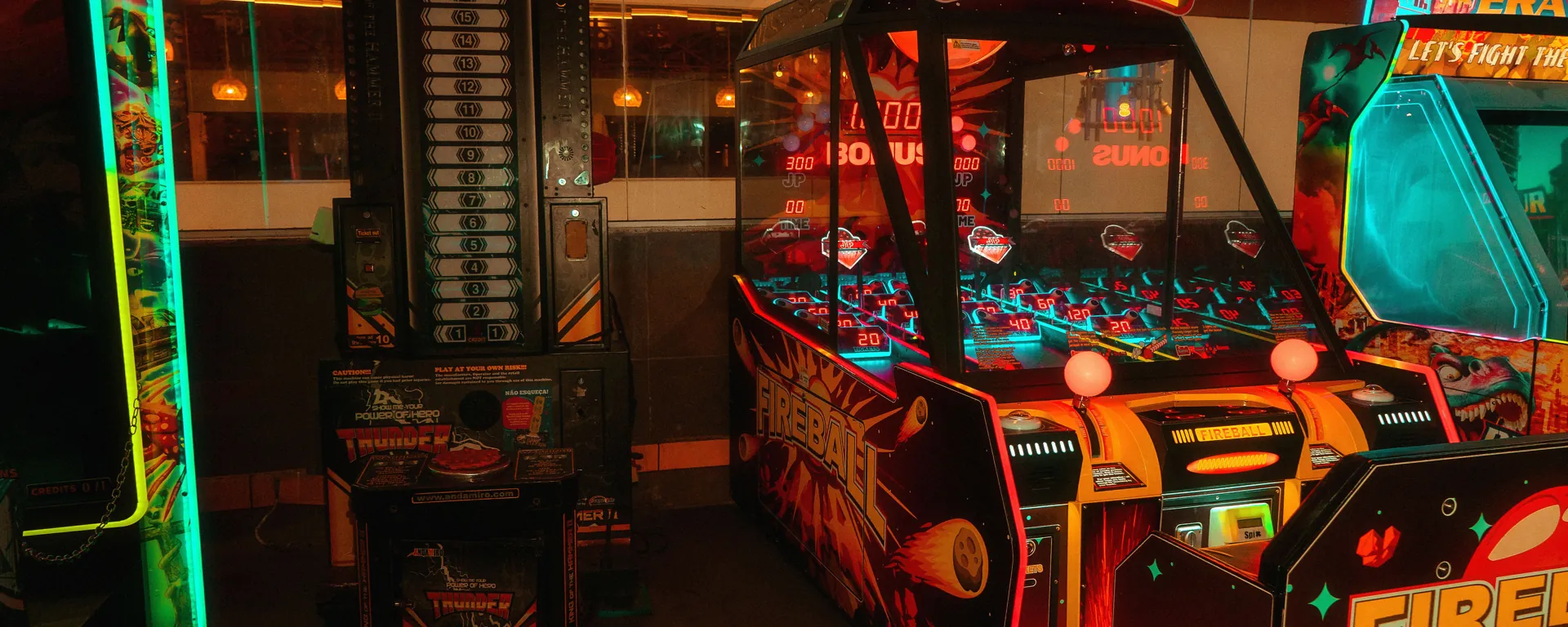 Glowing arcade machines in a dark, warm-lit game room